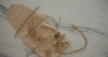 Elegant jewelry arrangement on marble slab, featuring gold pieces and hands